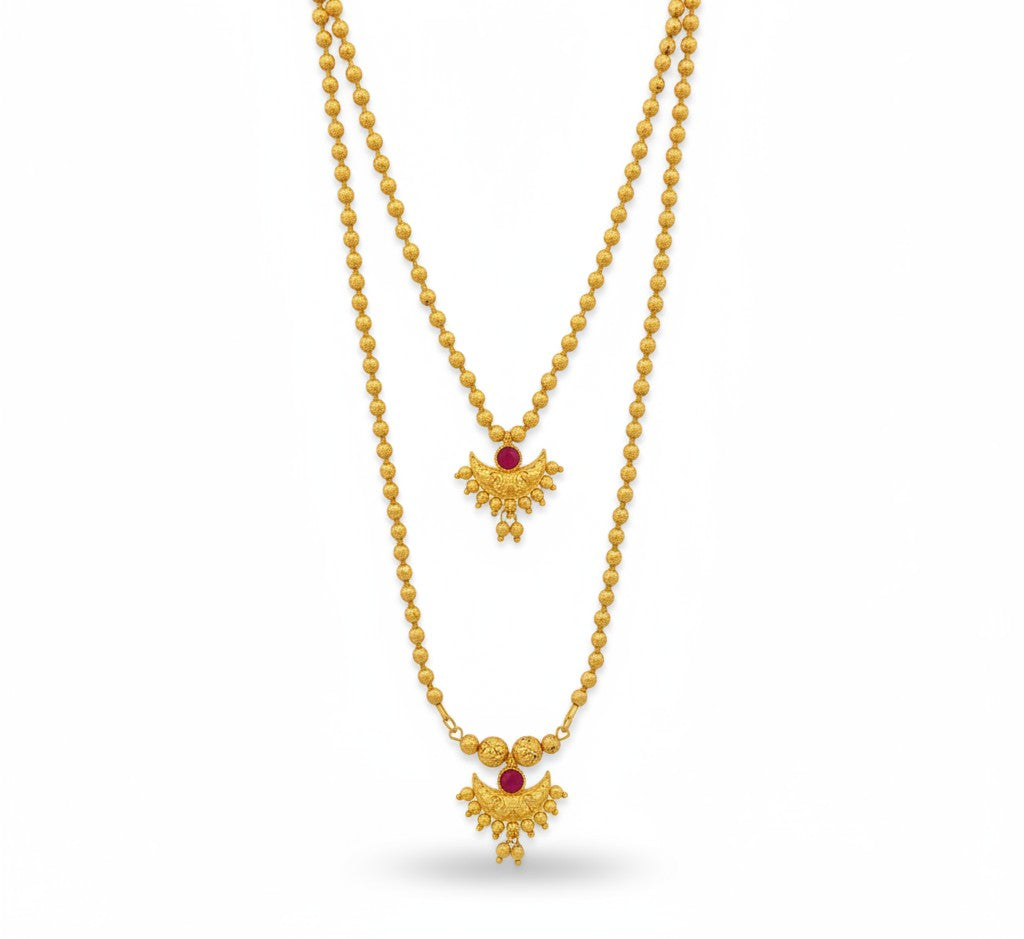 Woman wearing a gold necklace with a green top against a gray background