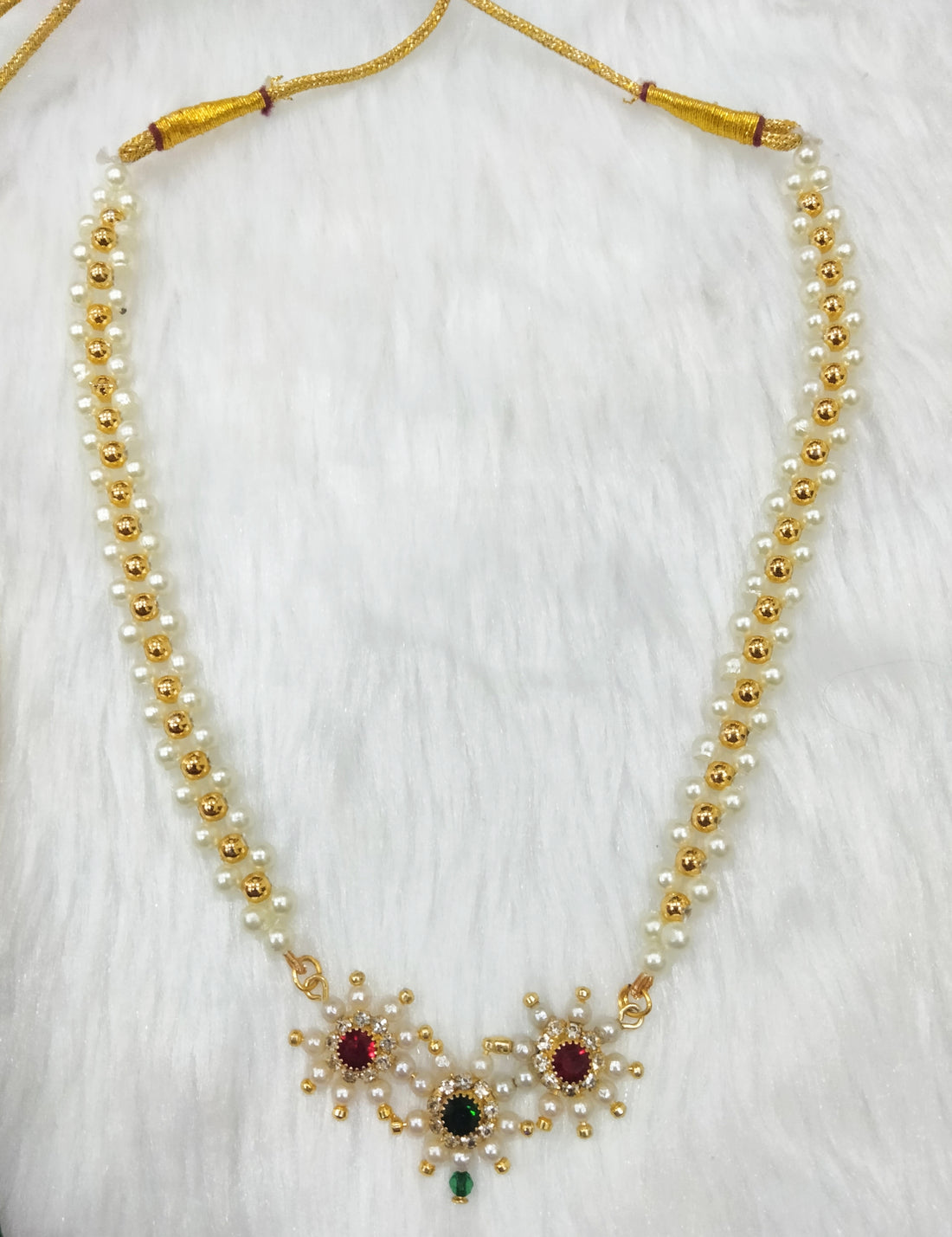 Pearl necklace with gold accents and gemstones on a white background